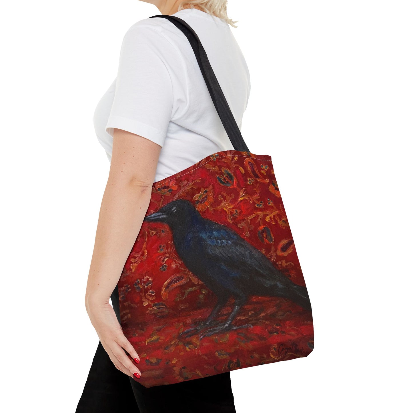 Person holding a tote bag with a black bird design on a red background